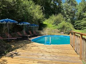 a swimming pool with chairs and umbrellas on a wooden deck at Domaine Lapin Qui Rit , chambre Céline in Saint-Jean-de-Côle