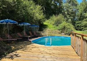 a swimming pool with chairs and umbrellas on a wooden deck at Domaine Lapin Qui Rit , chambre Céline in Saint-Jean-de-Côle +8 photos