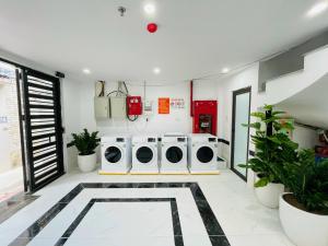 a laundry room with three washing machines and plants at Salahomes Apartment by Dapano in Hanoi