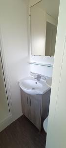 a white bathroom with a sink and a mirror at Mobilhome climatisé 3 chambres à 30 min du Puy du F et de Nantes in La Boissière-de-Montaigu +2 photos