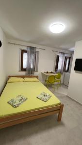 a bedroom with a yellow bed and a table at Royal Garden Apartments & Gastronomy in Budva