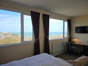 een hotelkamer met een bed en twee grote ramen bij Geckos Rest in Newquay