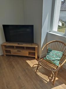 Il comprend un salon avec une chaise et une télévision à écran plat. dans l'établissement Maison entre Aven et Belon - Riec sur Belon, à Riec-sur-Bélon