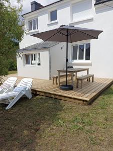 une terrasse en bois avec une table de pique-nique et un parasol dans l'établissement Maison entre Aven et Belon - Riec sur Belon, à Riec-sur-Bélon