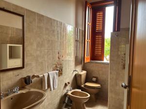 a bathroom with a sink and a toilet and a window at Garden Paradise near the sandy beach, parking & wifi in Marina dʼAvola +37 photos