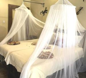 - un lit blanc avec des moustiquaires au-dessus dans l'établissement Thebe River Safaris, à Kasane