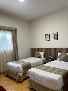 塔布克的住宿－اجنحة مجمع القوافل الفندقيه，酒店客房设有两张床和窗户。