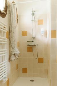 ein Bad mit einer Dusche mit orangefarbenen und weißen Fliesen in der Unterkunft Hôtel Les Fougères in Hossegor