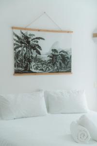 uma imagem de palmeiras numa parede acima de uma cama em Hôtel Les Fougères em Hossegor