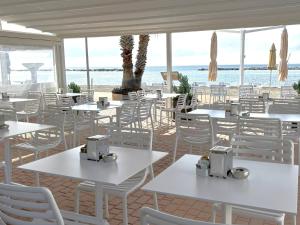 restauracja z białymi stołami i krzesłami oraz oceanem w obiekcie Hotel Delle Rose w mieście San Bartolomeo al Mare