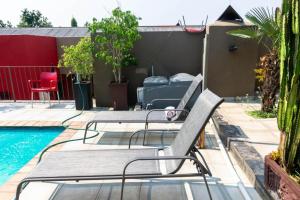 a patio with two chairs and a swimming pool at RAMATA GUEST HOUSE in Pretoria