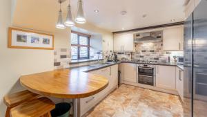 a kitchen with white cabinets and a wooden table at Mill Top in Ambleside