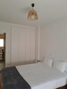 a bedroom with a white bed and a light fixture at apartamento perto do Santuário in Fátima
