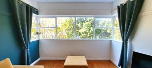 a room with a window with green curtains and a bench at Secure Modern 2 bed - excellently located in Cape Town