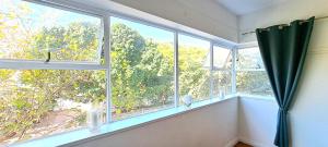um quarto com duas janelas com cortinas verdes em Secure Modern 2 bed - excellently located na Cidade do Cabo
