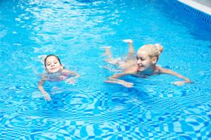 deux jeunes filles nageant dans une piscine dans l'établissement Starlet Hotel, à Nha Trang