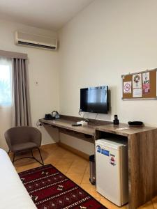 een kamer met een bureau, een televisie en een koelkast bij اجنحة مجمع القوافل الفندقيه in Tabuk