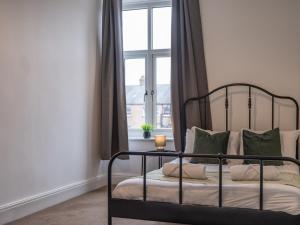 a bedroom with a black bed with pillows and a window at Large Group Central Apartment in Newcastle upon Tyne