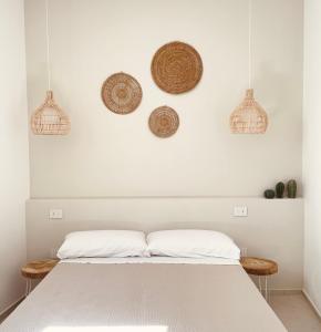a bedroom with a white bed with baskets on the wall at Camere Assúd in Leuca