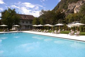 une grande piscine avec des chaises et des parasols dans l'établissement Victoria Jungfrau Grand Hotel & Spa, à Interlaken