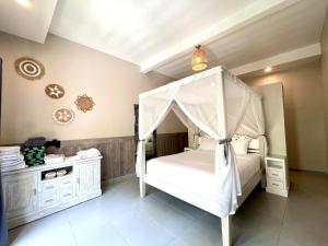 1 dormitorio con 1 cama blanca con dosel en Frangipani Villa Seminyak, en Seminyak