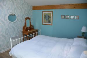 a bedroom with a white bed and a blue wall at Large 3 bedroom Cottage near Ruffec in Bernac