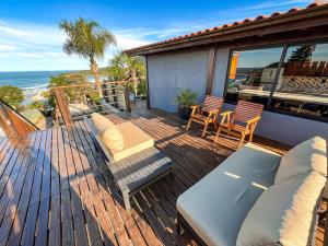 a patio with a couch and chairs on a deck at Pousada Descanso do Rei - Vista Para o Mar & Melhor Localização da Praia do Rosa in Praia do Rosa