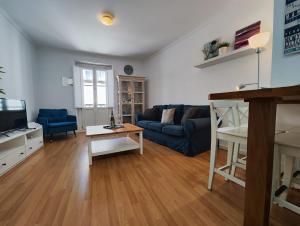 - un salon avec un canapé bleu et une table dans l'établissement Dulce Arbolí Little Apartments, à Cadix