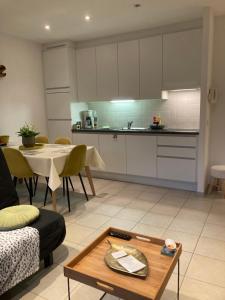 a living room with a table and a kitchen at DUNAS, appartement, garage, 200m van strand en centrum in Koksijde