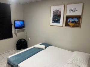 ein Schlafzimmer mit einem Bett und einem TV an der Wand in der Unterkunft Casa com visão panorâmica no centro de Nova Trento in Nova Trento