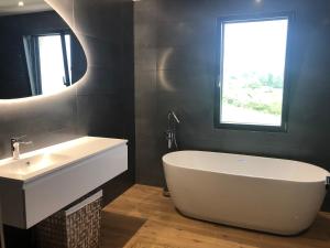 een badkamer met een bad, een wastafel en een raam bij La Villa in Brive-la-Gaillarde