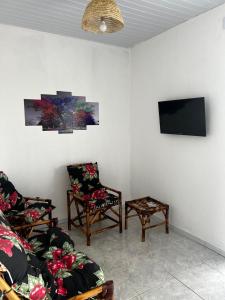 a living room with two chairs and a flat screen tv at Pousada Riviera - Praia de Lagoa do Pau in Coruripe