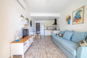 a living room with a blue couch and a kitchen at Sol y mar maspalomas in Maspalomas