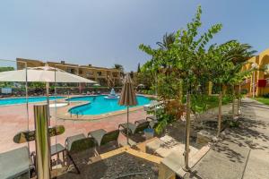 a resort with a swimming pool with chairs and an umbrella at Sol y mar maspalomas in Maspalomas