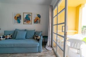 a living room with a blue couch and a glass door at Sol y mar maspalomas in Maspalomas
