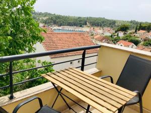 - Balcón con mesa de madera y 2 sillas en Apartments Dante Domus Aurea, en Milna