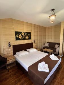 um quarto com uma cama grande e um sofá em Family Hotel Emaly 2 em Sapareva Banya