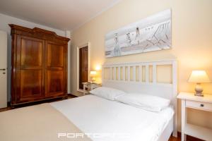PortofinoVip by PortofinoVip في بورتوفينو: غرفة نوم بسرير أبيض وخزانة خشبية