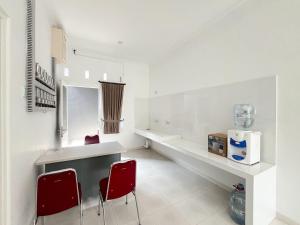 a kitchen with two red chairs and a counter at RedDoorz at Griya Martha Sumber Solo in Bonorejo