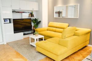 salon z żółtą kanapą i telewizorem w obiekcie Casa de Dinca, 2 bedroom, big balcony, free parking zone w Zagrzebiu