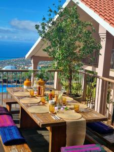 - une longue table en bois sur une terrasse avec vue sur l'océan dans l'établissement Yeotown Health Retreat, à Arco da Calheta