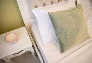 ein weißes Bett mit einem grünen Kissen und einem Tisch in der Unterkunft Anais Studio in Mamaia