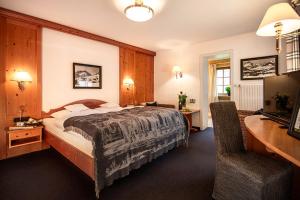 a hotel room with a large bed and a desk at Gästehaus Daheim in Riezlern