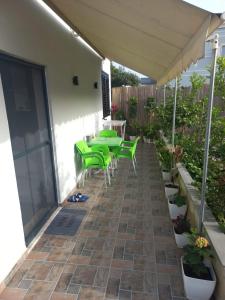 um pátio com mesas verdes e cadeiras debaixo de um guarda-sol em Private Villa Aras -Pleasure of Elegance & Serenity em Vlorë