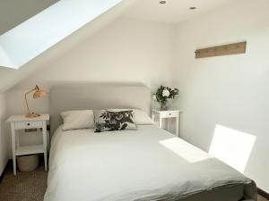 um quarto com uma cama branca e 2 mesas brancas em The Barn em Chichester