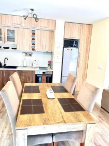 a kitchen with a wooden table with chairs and a refrigerator at Апартамент Франческа in Varna City