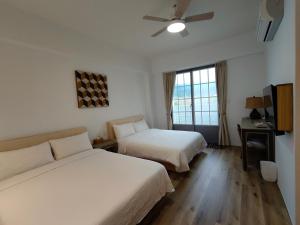 a hotel room with two beds and a ceiling fan at 小時公館 in Yuli