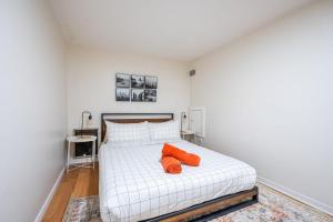 a bedroom with a white bed with two orange pillows at Modern 2BR Queen Beds - Close to Bellwoods Park in Toronto