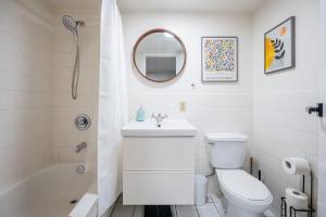a white bathroom with a toilet and a sink at Modern 2BR Queen Beds - Close to Bellwoods Park in Toronto
