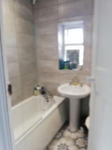 a white bathroom with a sink and a tub and a sink at Entire House in Belfast +6 photos